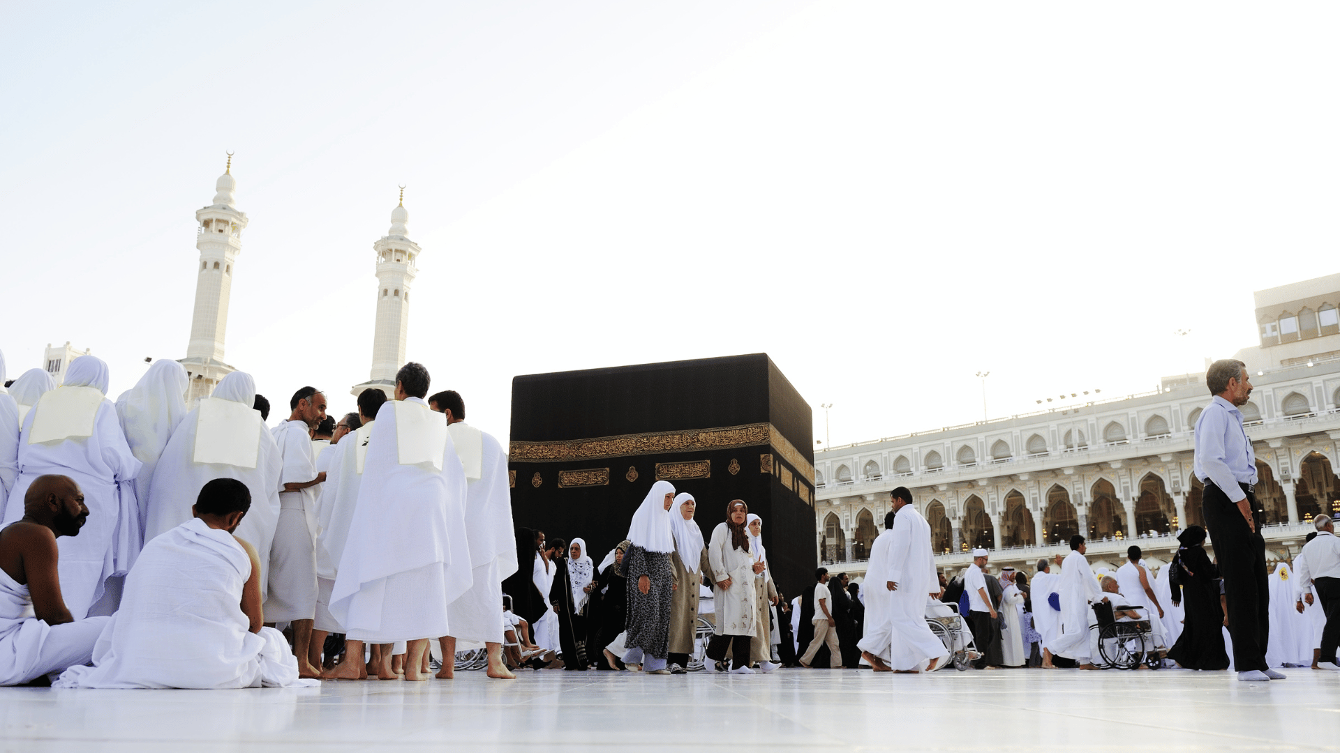 Pilgrims in white ihram garments congregating around the Kaaba in Mecca, feeling like they are coming home.